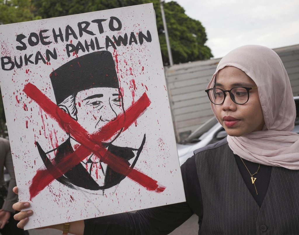 A woman holds a placard depicting the late president Suharto during a rally against proclaiming him a national hero in Jakarta, Indonesia, on Thursday. Photo: Kyodo