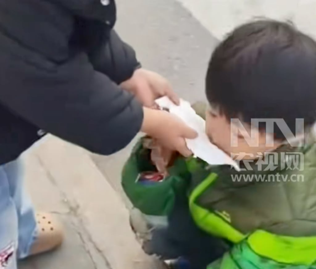 A passer-by helps little Yueyue blow her runny nose with a tissue as she sits on the street. Photo: Douyin A passer-by helps little Yueyue blow her runny nose with a tissue as she sits on the street. Photo: Douyin