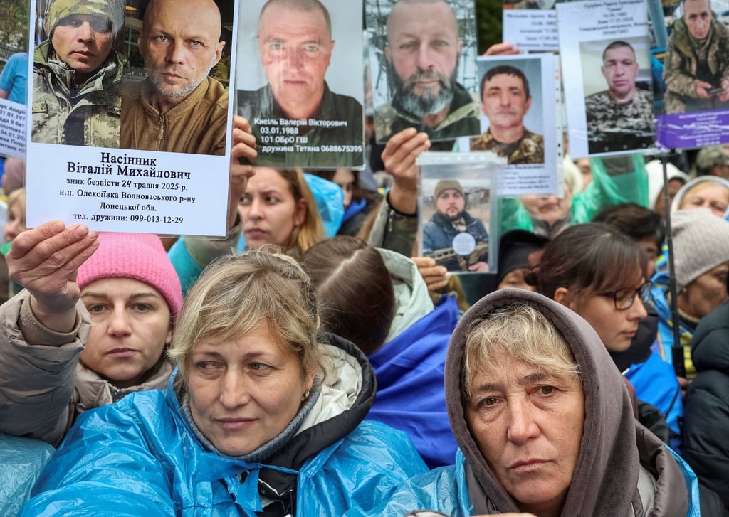 People hold portraits of their relatives, Ukrainian POWs, hoping they will be recognised by others as they return after a swap, in an undisclosed location in Ukraine on October 2. Photo: Reuters People hold portraits of their relatives, Ukrainian POWs, hoping they will be recognised by others as they return after a swap, in an undisclosed location in Ukraine on October 2. Photo: Reuters