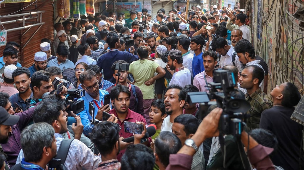 Local residents and journalists rush out into the streets after the railing of a building collapsed during an earthquake in Dhaka on Friday. Photo: EPA