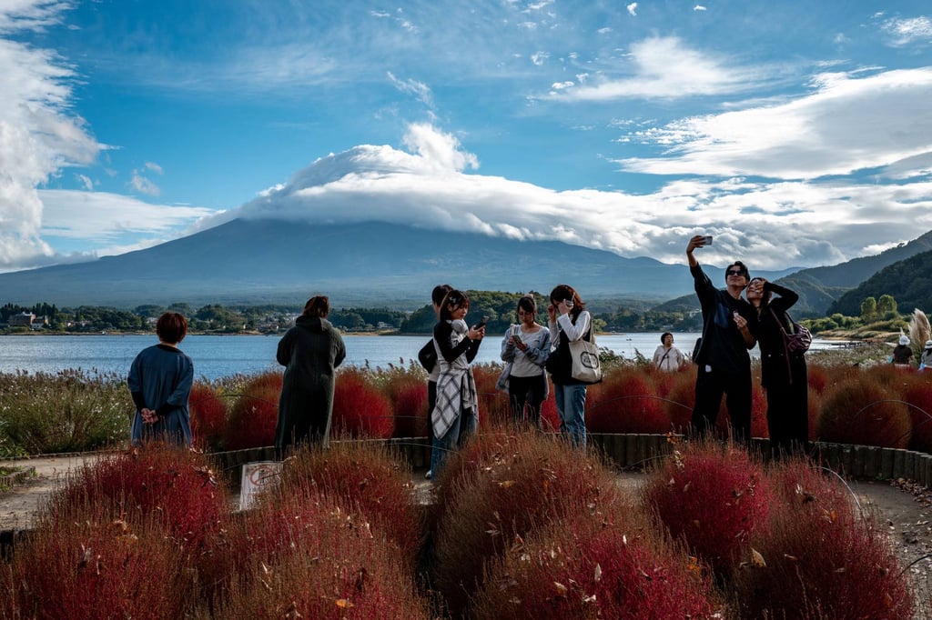 Tourists take pictures with Mount Fuji in the background in Yamanashi prefecture, Japan. China has issued several travel warnings urging its citizens to avoid Japan amid a diplomatic row over Taiwan. Photo: AFP Tourists take pictures with Mount Fuji in the background in Yamanashi prefecture, Japan. China has issued several travel warnings urging its citizens to avoid Japan amid a diplomatic row over Taiwan. Photo: AFP