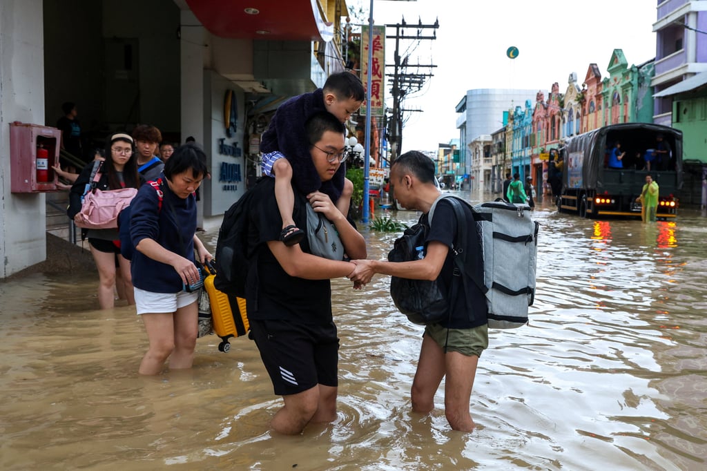 Tourists wade through a flooded area in Hat Yai district, Songkhla, Thailand, on Sunday. Officials have warned floodwaters are yet to peak. Photo: Reuters