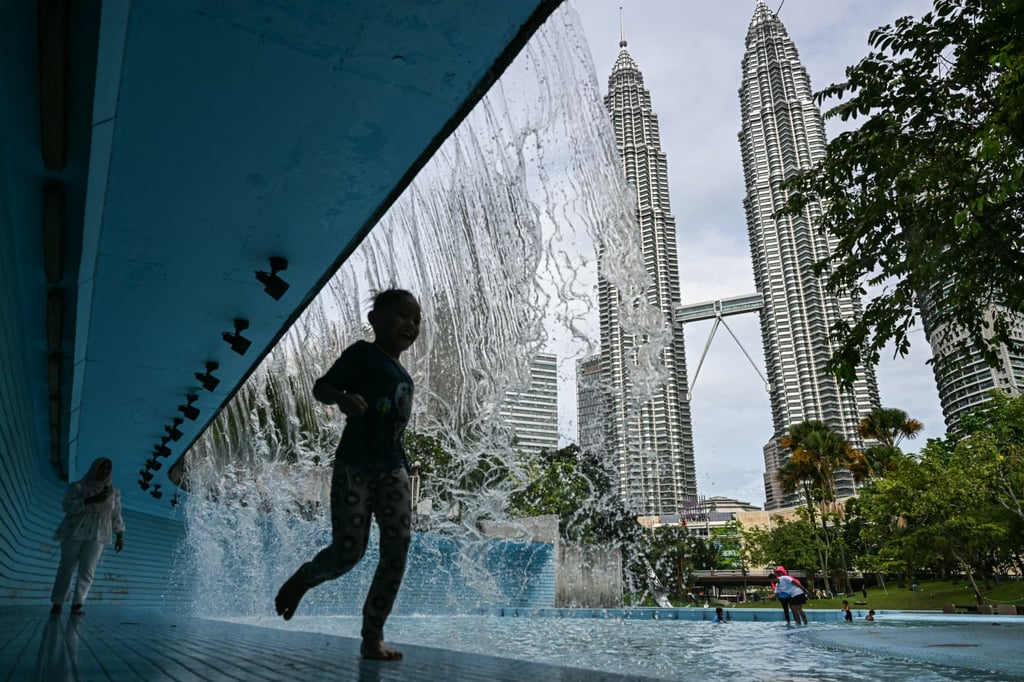 A child plays at a public pool in front of Malaysia’s Petronas Twin Towers in Kuala Lumpur. Photo: AFP