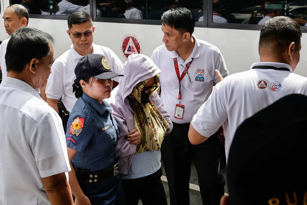 One of eight arrested Department of Public Works and Highways officers is escorted by a police officer to the Sandiganbayan anti-corruption court in Quezon City, the Philippines, on Monday. Photo: EPA