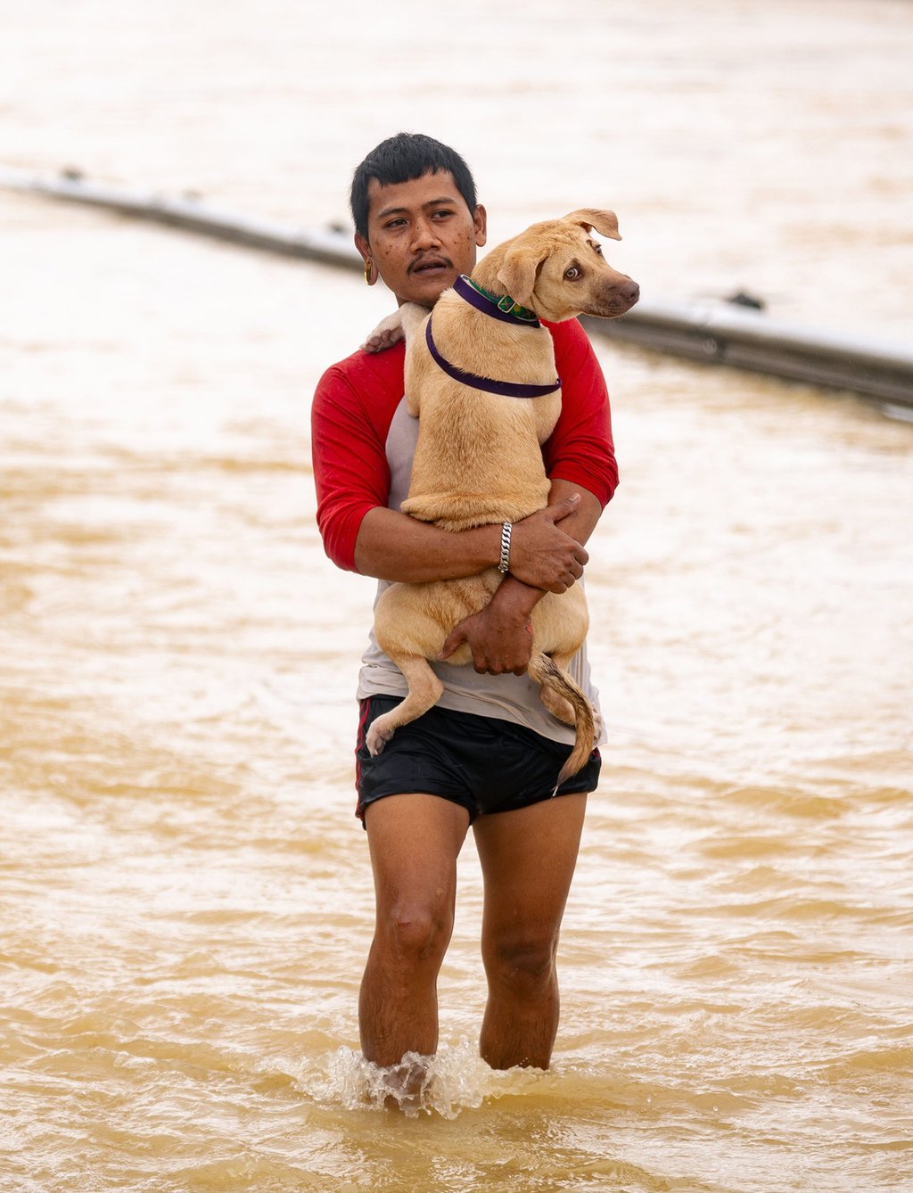 A man holding his pet dog wades through flood in Hat Yai on Tuesday. Photo: Xinhua