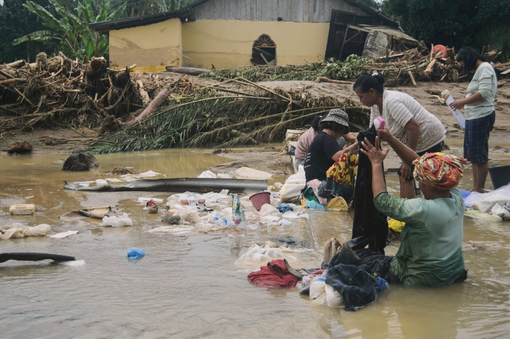 People use flood water on Saturday to remove mud from clothes at a village in North Sumatra, Indonesia. Photo: AP