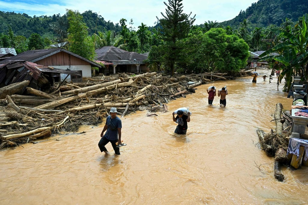 People wade through floodwaters in the aftermath of flash floods in Central Tapanuli, North Sumatra province, on Tuesday. North Sumatra suffered the heaviest toll with more than 300 people dead. Photo: AFP People wade through floodwaters in the aftermath of flash floods in Central Tapanuli, North Sumatra province, on Tuesday. North Sumatra suffered the heaviest toll with more than 300 people dead. Photo: AFP