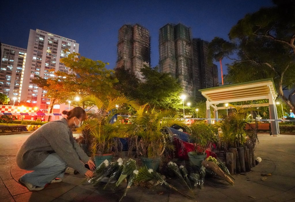 A mourner pays tribute to the victims of the Tai Po fire by leaving flowers near Wang Fuk Court, on November 28. Photo: Alexander Mak