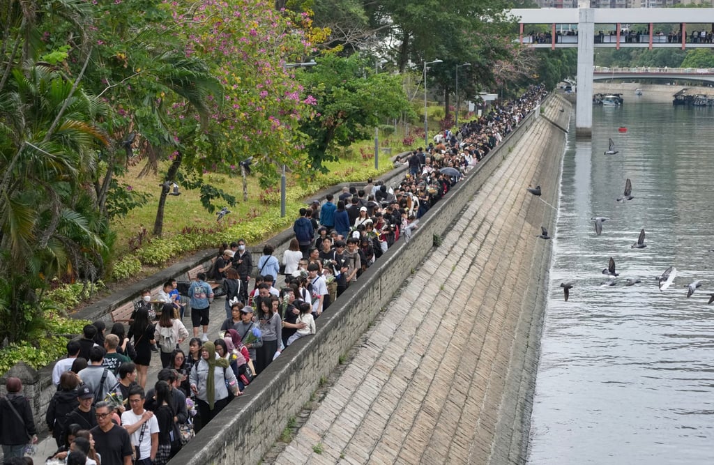 People lay flowers in tribute to the victims of the blaze; the queue of mourners stretches beyond Tai Po’s Po Heung Bridge on Sunday. Photo: Karma Lo