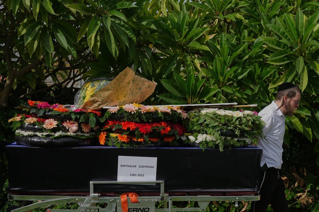 A funeral worker wheels the coffin of Sudthisak Rinthalak on Tuesday. Photo: AP