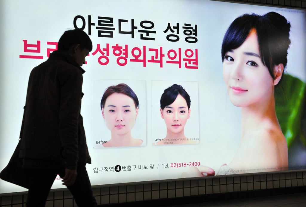 A pedestrian passes an advertisement for a plastic surgery clinic in a Seoul subway station. Photo: AFP A pedestrian passes an advertisement for a plastic surgery clinic in a Seoul subway station. Photo: AFP
