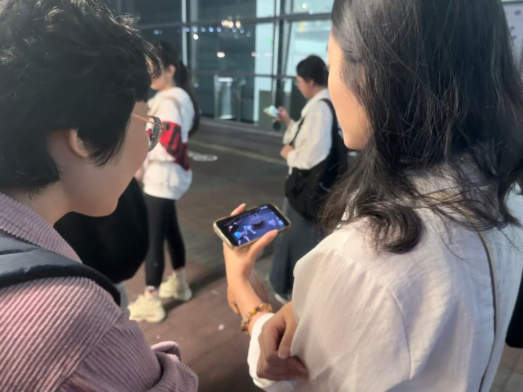 Fans watch the action on a phone as they wait for prices to drop outside the Coliseum. Photo: Stephy Zhang