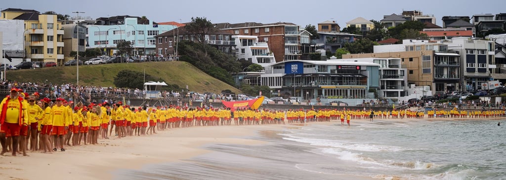 Lifeguards line the Bondi Beach shoreline on Saturday to observe three minutes of silence for the victims of Sunday’s shootings. Photo: AAP/AP