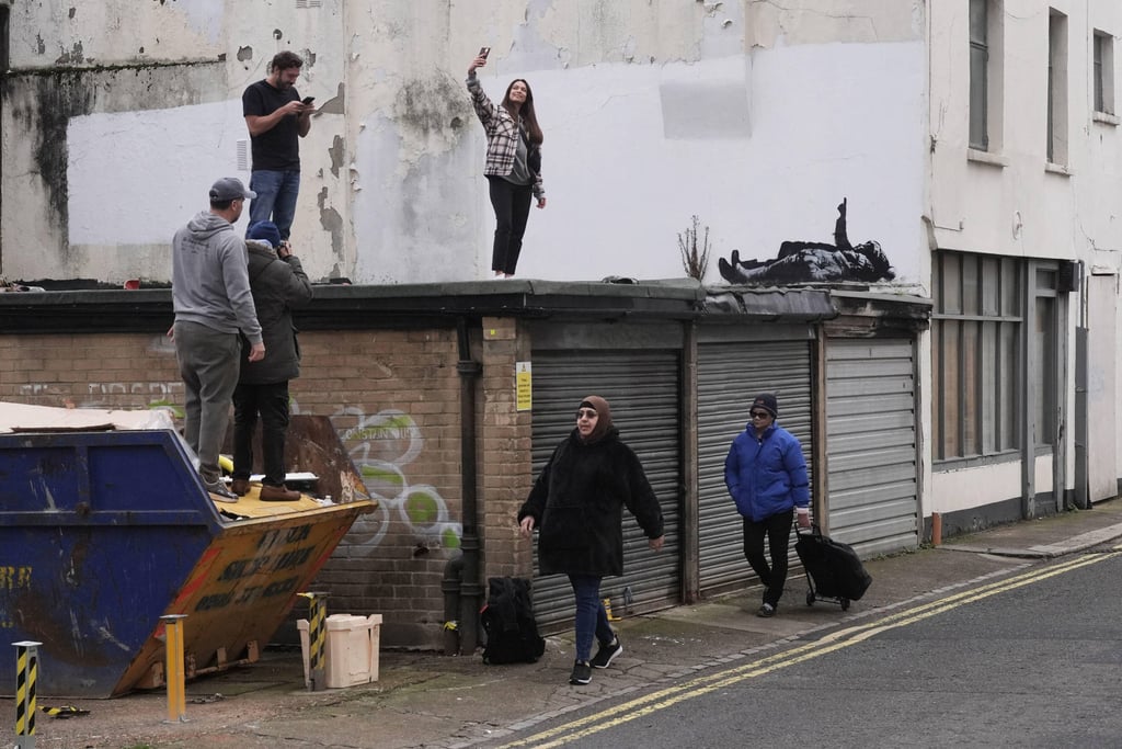 A person takes a selfie with the new Banksy piece. Photo: PA via AP