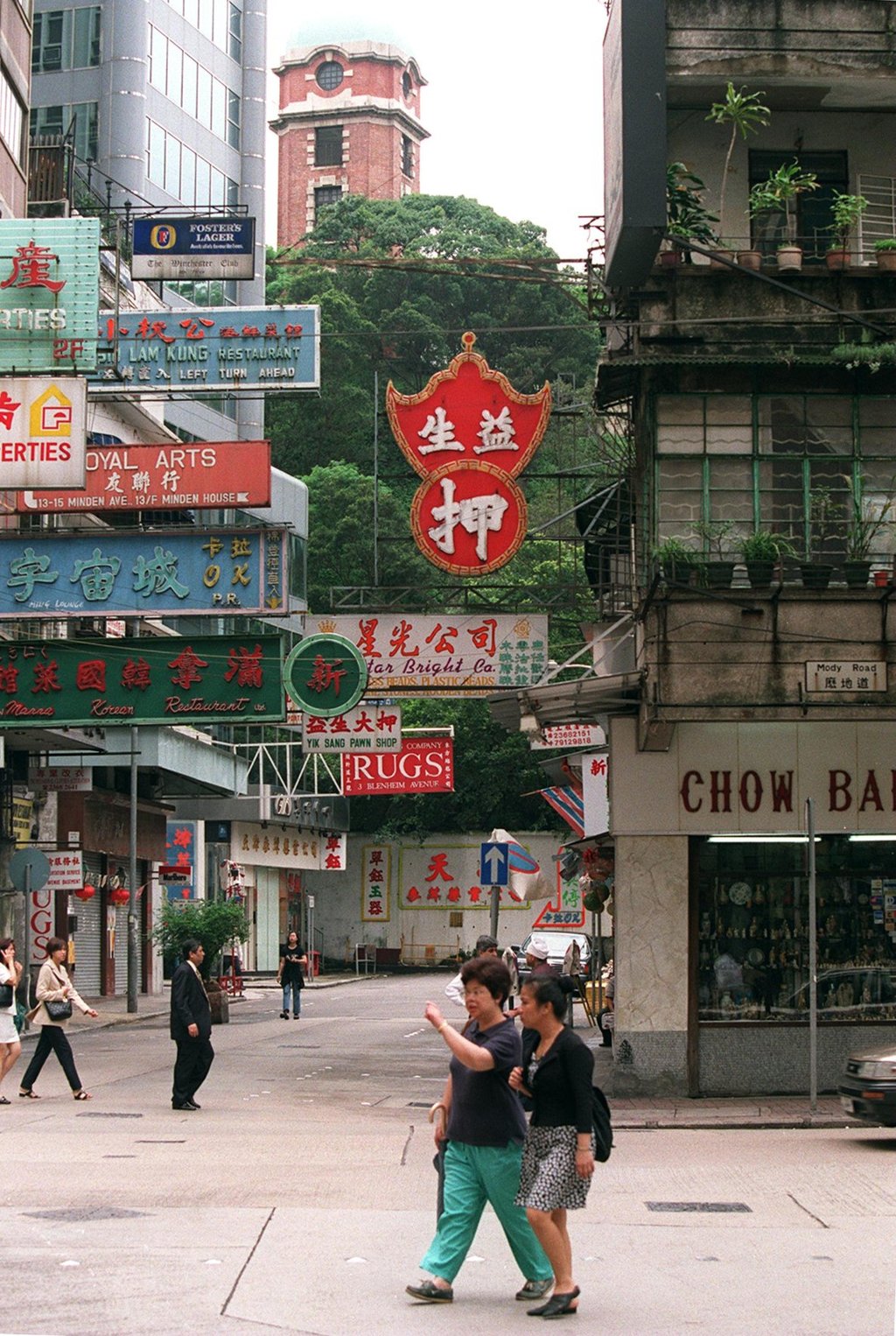 Pedestrians walk around Hong Kong’s Tsim Sha Tsui shopping district in 1997, with the red-brick Signal Tower and lush Signal Hill Garden in the background. Photo: SCMP Pictures
