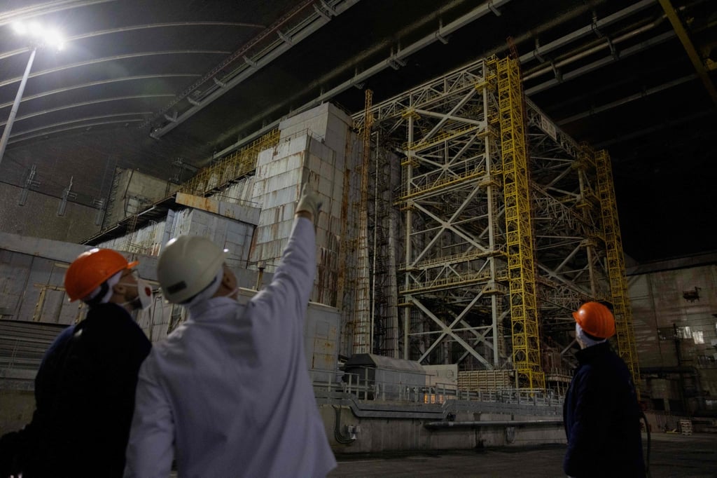 A Chernobyl worker points to structural damage on December 22, 2025, following a February drone strike that compromised the containment shell. Photo: AFP