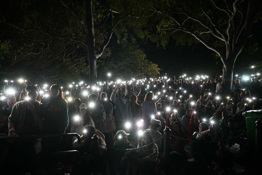 People turn on their mobile phones’ flashlights on December 31 in Sydney as they observe a minute’s silence an hour before midnight, to reflect on the Bondi Beach shooting. Photo: AFP
