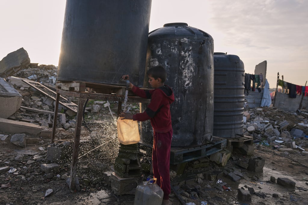 A Palestinian boy collects water from a tank set up in Gaza City. Photo: AP