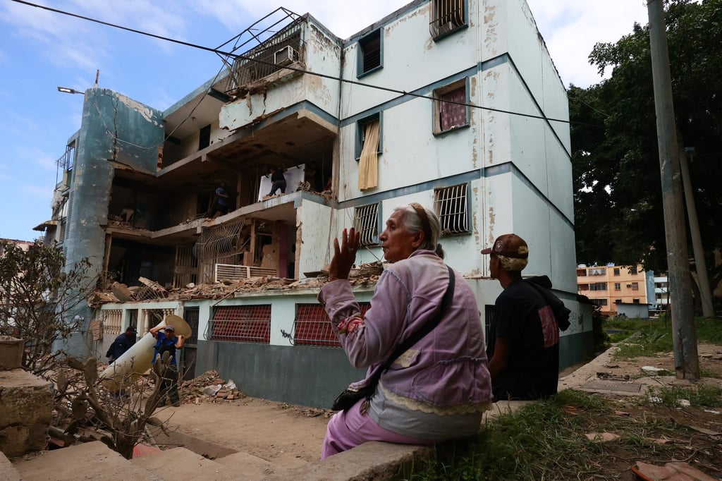 Two people sit in front of a building in La Guaira, Venezuela, that was destroyed in a US bombing raid, as others remove rubble, on January 4. Photo: dpa Two people sit in front of a building in La Guaira, Venezuela, that was destroyed in a US bombing raid, as others remove rubble, on January 4. Photo: dpa