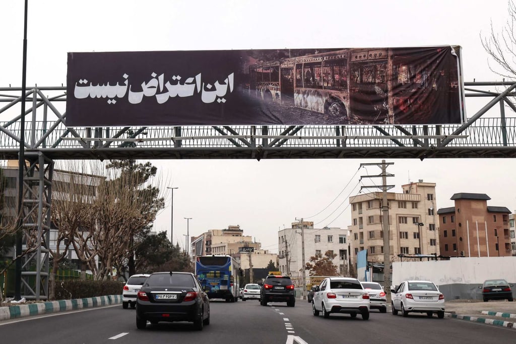 Cars drive under a banner that reads ‘This is not a protest’ in Tehran on Thursday. Photo: AFP