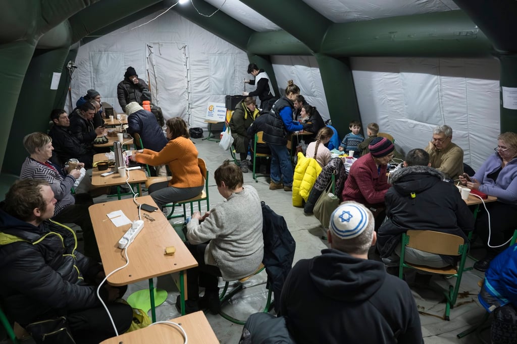 Kyiv locals inside a heated tent shelter where people can charge their devices, warm themselves and have hot drinks. Photo: EPA