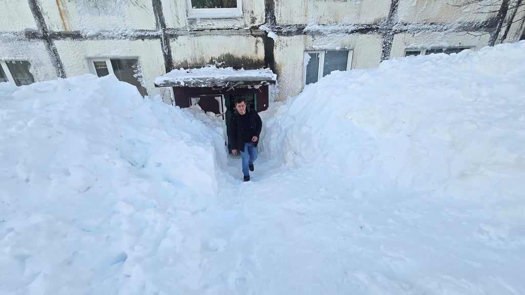 A man exits a residential block surrounded by snow. Photo: Lydmila Moskvicheva via Reuters
