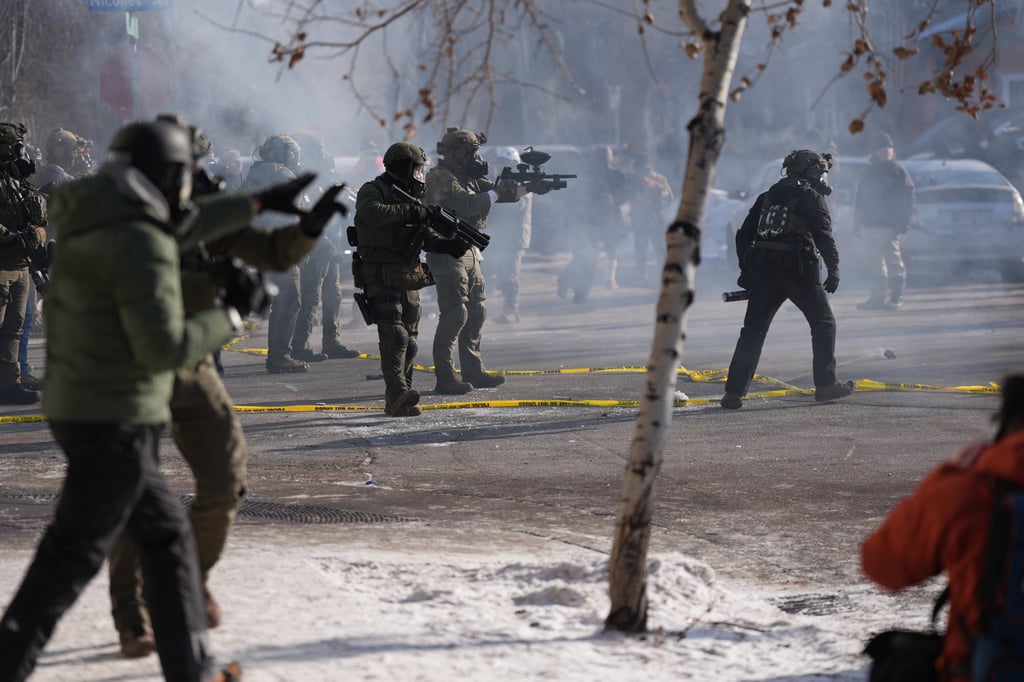 Federal immigration officers use tear gas against observers after a shooting in Minneapolis on Saturday. Photo: AP