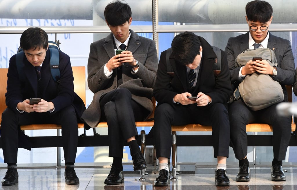 Job seekers look at their smartphones while during an employment fair in Seoul. Photo: AFP Job seekers look at their smartphones while during an employment fair in Seoul. Photo: AFP