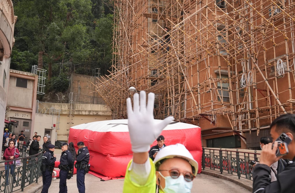 Fire Services Department officers set up a rescue cushion beneath the scaffolding at Baguio Villa on Wednesday. Photo: Elson Li Fire Services Department officers set up a rescue cushion beneath the scaffolding at Baguio Villa on Wednesday. Photo: Elson Li