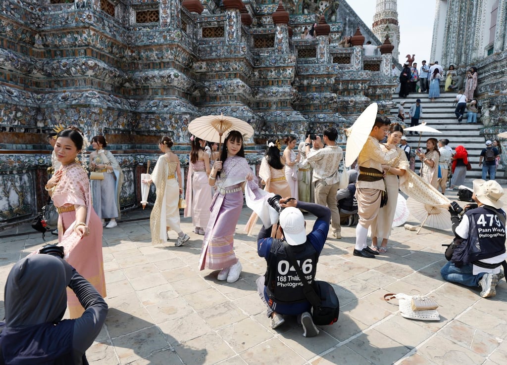 1 月 19 日，身着泰国传统服装的游客在曼谷黎明寺摆姿势拍照留念。照片：EPA