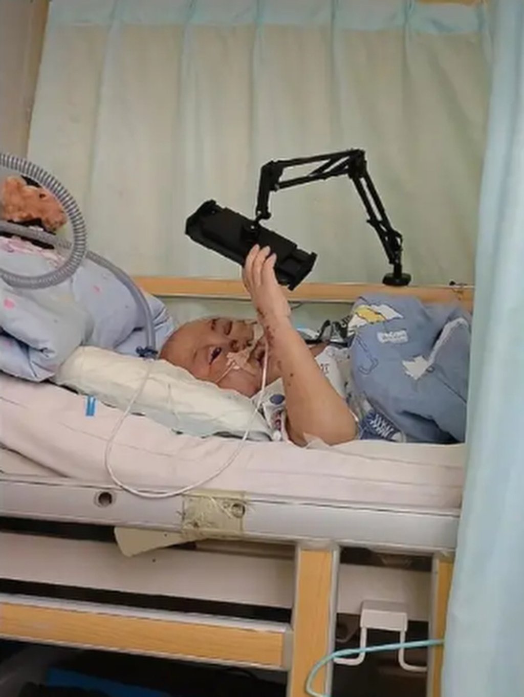 Haohao is playing with his mobile phone as he lies stricken with illness in his hospital bed. Photo: QQ.com