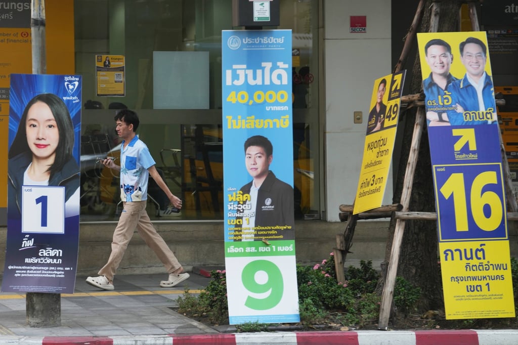 A man walks behind political parties’ election campaign posters in Bangkok, Thailand, on Wednesday. Photo: AP