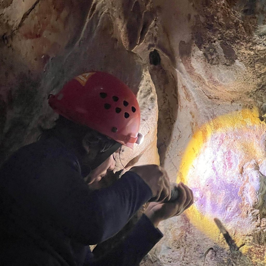 Scientist Adhi Agus Oktaviana studies handprints on the walls of a cave in Sulawesi, Indonesia. Photo: Maxime Aubert/AP