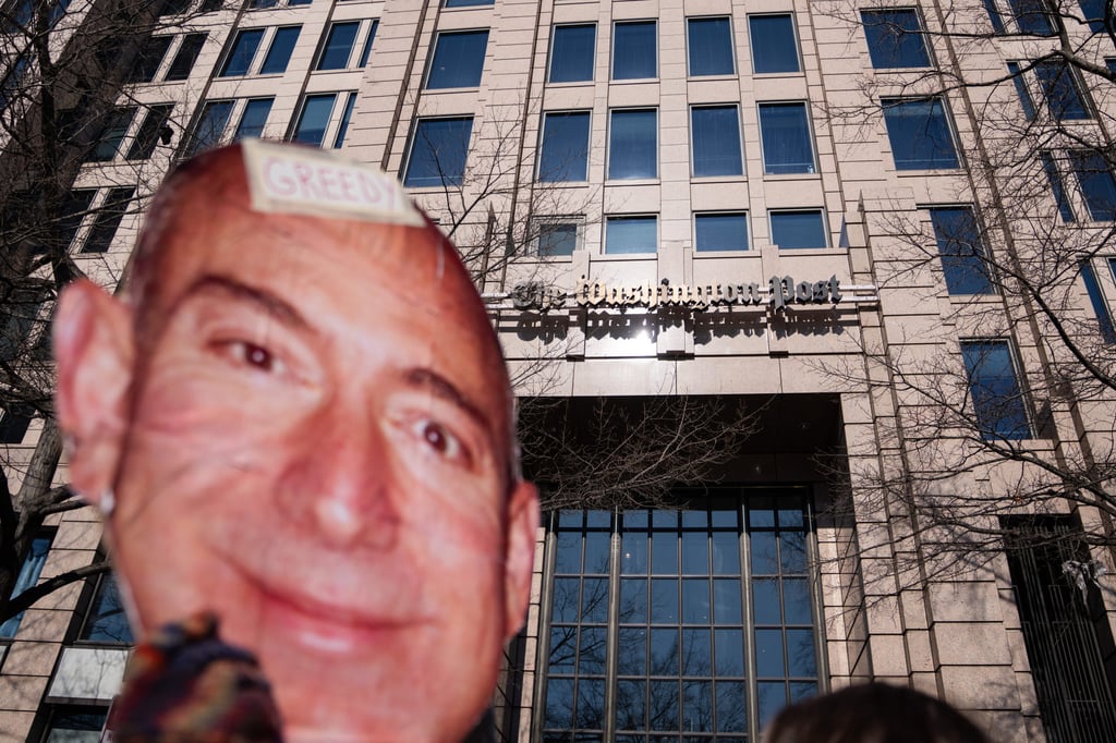 Um manifestante segurou um recorte do rosto de Jeff Bezos do lado de fora do Washington Post Office na quinta-feira. Foto: AP Um manifestante segurou um recorte do rosto de Jeff Bezos do lado de fora do Washington Post Office na quinta-feira. Foto: AP