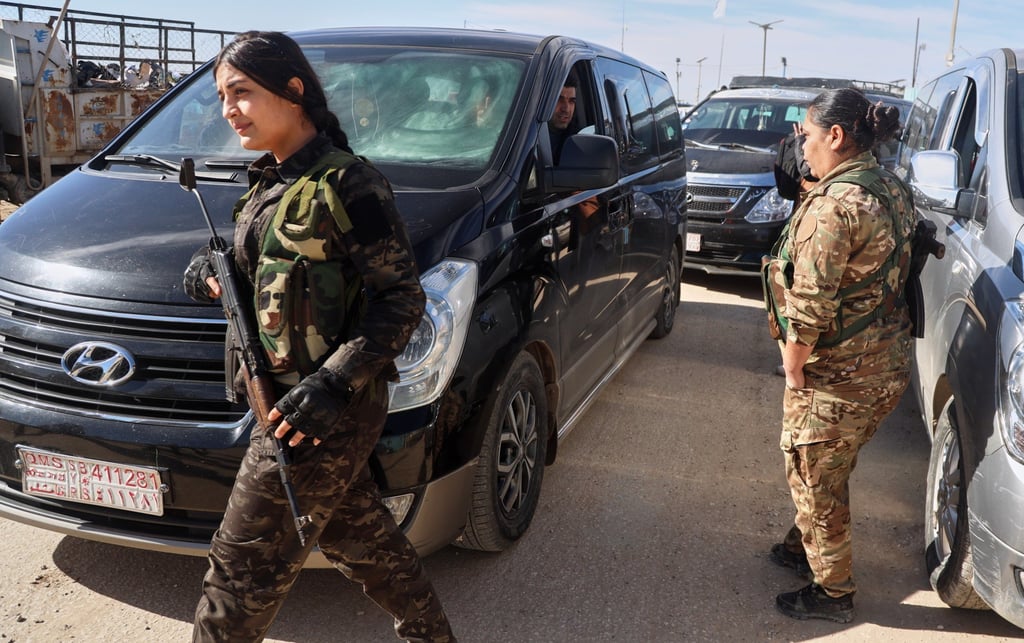 Syrian Democratic Forces members secure the area as vans carrying Australian family members of suspected Islamic State militants head to the airport on Monday. Photo: AP Syrian Democratic Forces members secure the area as vans carrying Australian family members of suspected Islamic State militants head to the airport on Monday. Photo: AP