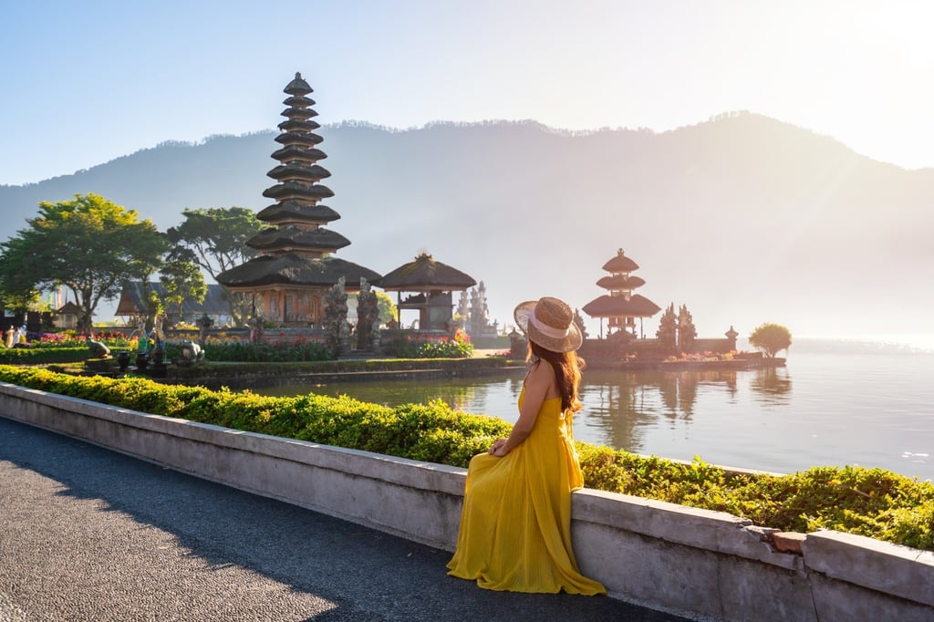 Seorang turis wanita muda sedang bersantai dan menikmati pemandangan indah di Pura Ulun Danu Beratan di Bali. Foto: Shutterstock