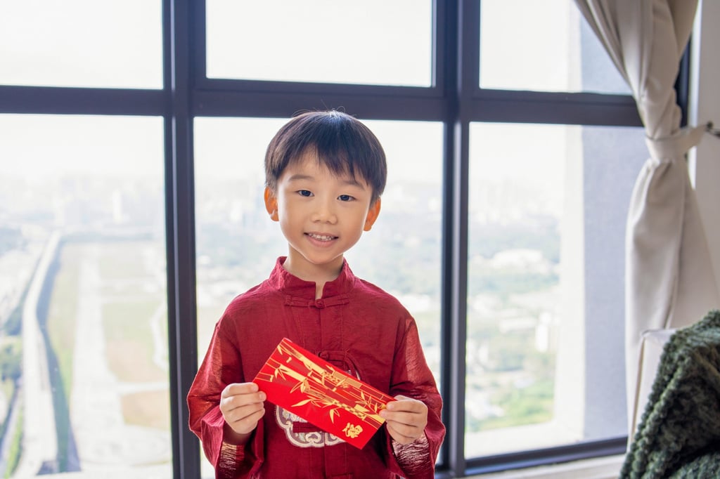 A little boy in traditional attire holds a lucky red envelope gift at home. Photo: Getty Images