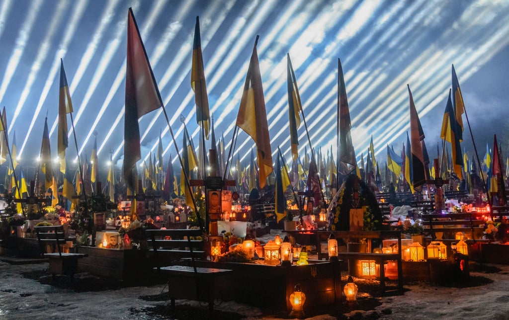 “Rays of Memory” light beams illuminate the graves of fallen Ukrainian soldiers during a joint prayer and candlelight vigil at Lychakiv Military Cemetery in Lviv on Monday. Photo: EPA