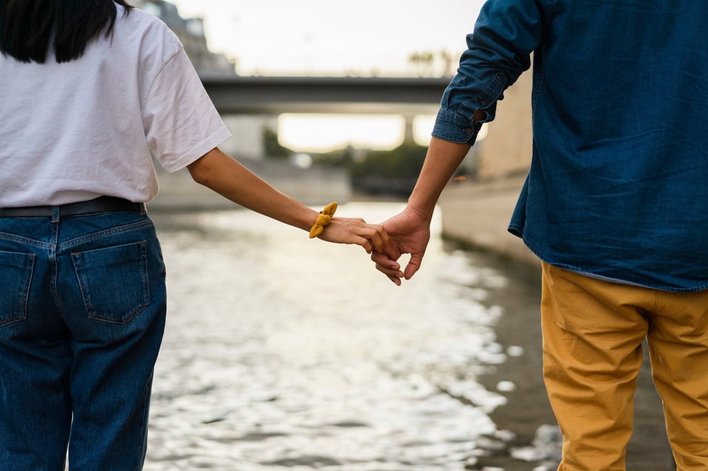 A couple holding hands on the banks of the River Seine in Paris, France. Photo: Getty Images