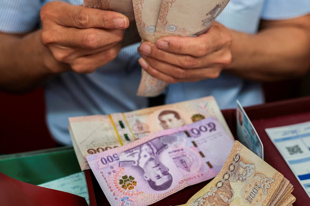 A cashier counts Thai baht banknotes. Each groom paid the bride’s family a dowry of 1 million baht. Photo: Reuters