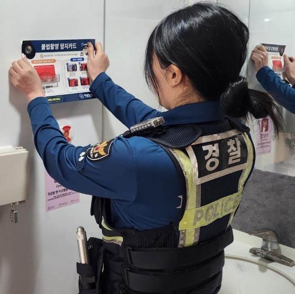 A police officer posts a notice showing how to detect illegal spycams inside a women’s restroom in Hanam, Gyeonggi province, on October 20, 2025. Photo: Hanam Police Station