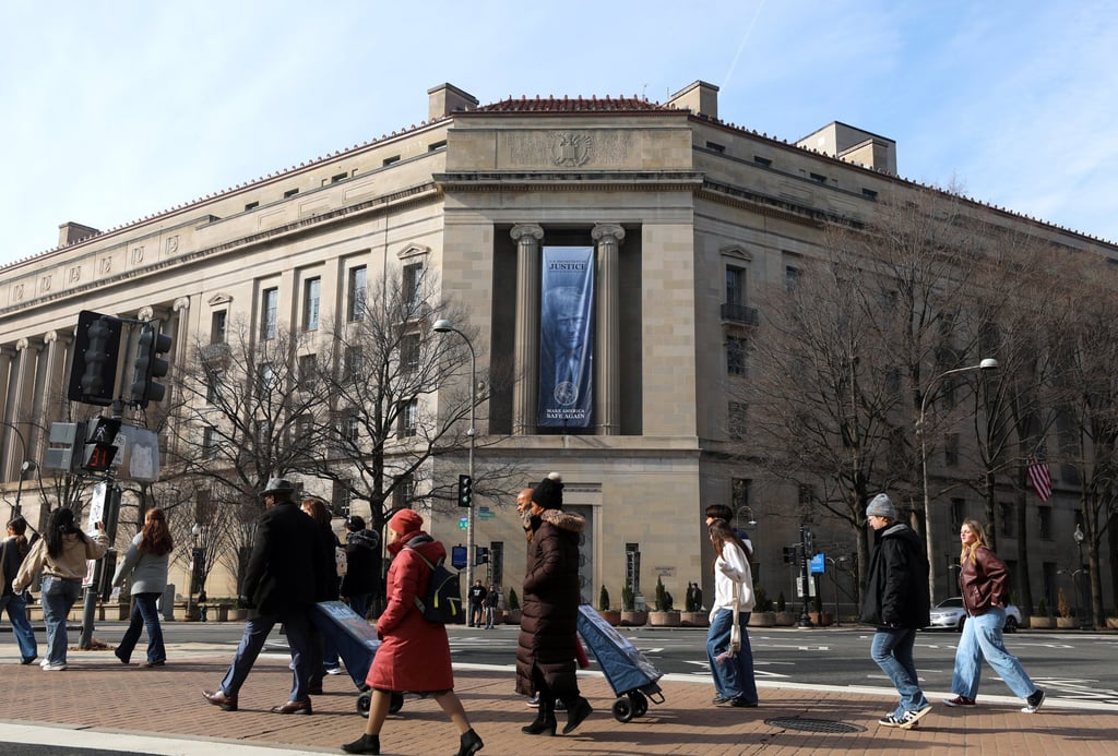 Tourists walk past a banner featuring US President Donald Trump hanging outside the Department of Justice in Washington on Friday. Photo: AP Tourists walk past a banner featuring US President Donald Trump hanging outside the Department of Justice in Washington on Friday. Photo: AP