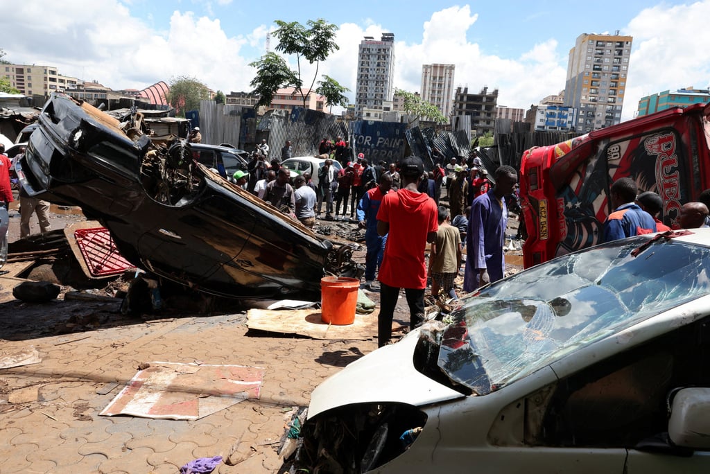 People stand near the wreckage of vehicles destroyed following heavy rainfall in Nairobi. Photo: Reuters