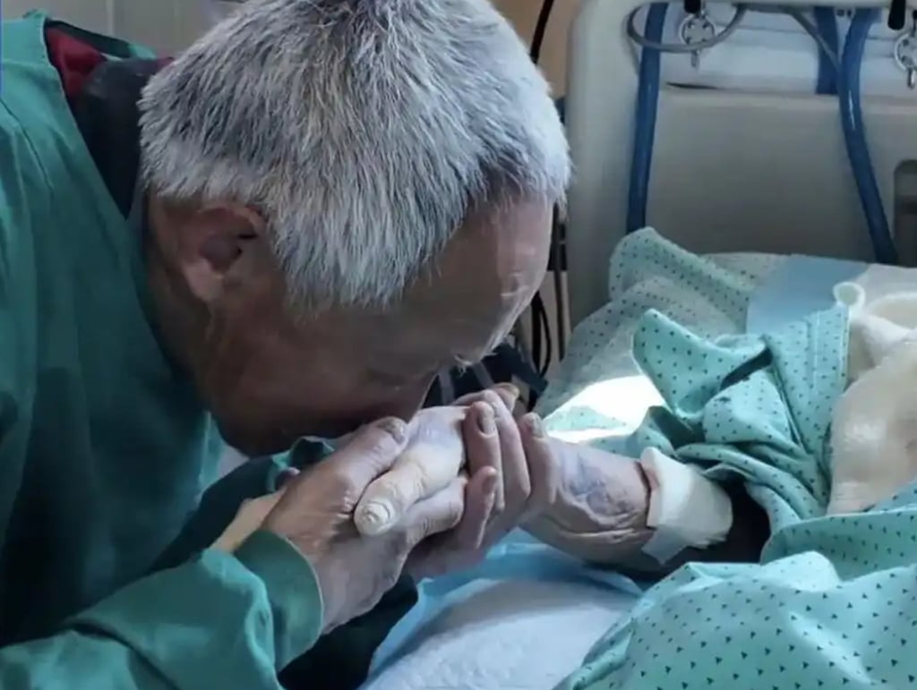 Touching: Chen Achong kisses his wife’s hand as she lies in her hospital bed. Photo: CCTV