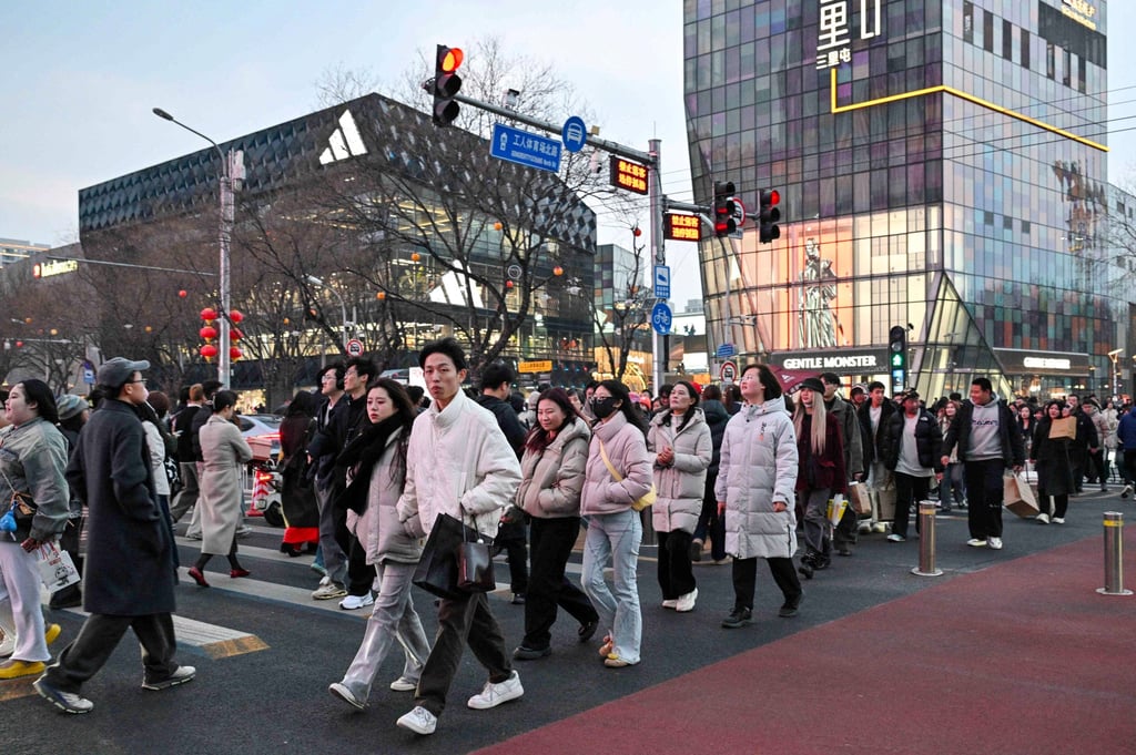 People cross a road near a shopping centre in Beijing on March 7. Photo: AFP