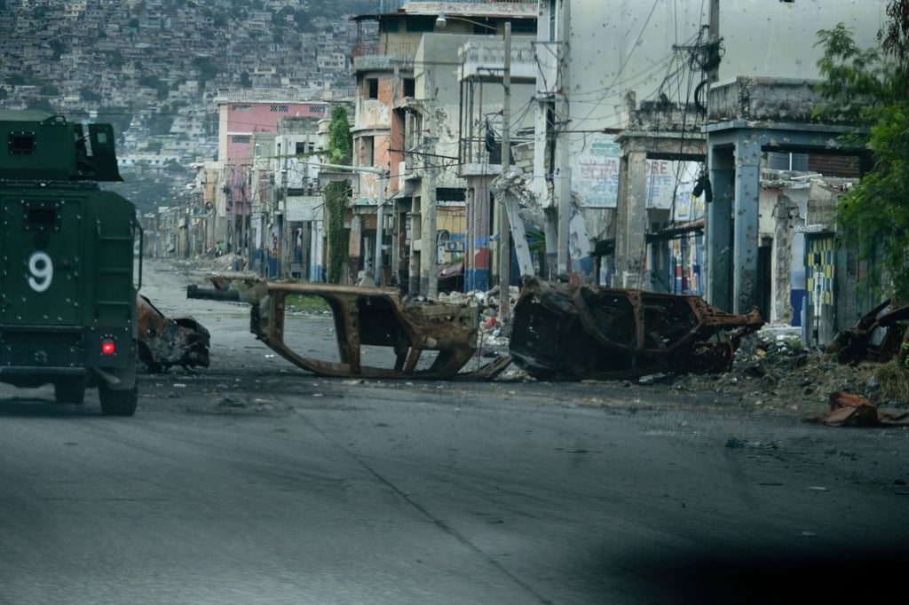 A police vehicle drives around cars burned by armed gangs in Port-au-Prince. Photo: AFP