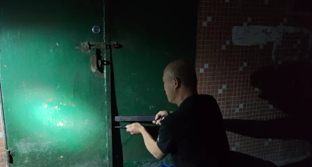 A police officer forces open the gate at the entrance to the trapped man’s home. Photo: QQ.com