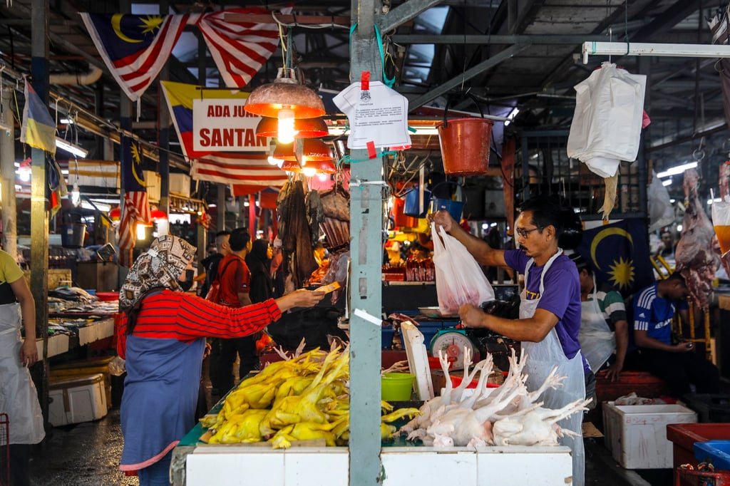 A customer buys a chicken from a vendor at a wet market in Kuala Lumpur. Malaysia’s traders say “a minimal adjustment in prices may be unavoidable” if cost pressures persist. Photo: EPA-EFE A customer buys a chicken from a vendor at a wet market in Kuala Lumpur. Malaysia’s traders say “a minimal adjustment in prices may be unavoidable” if cost pressures persist. Photo: EPA-EFE