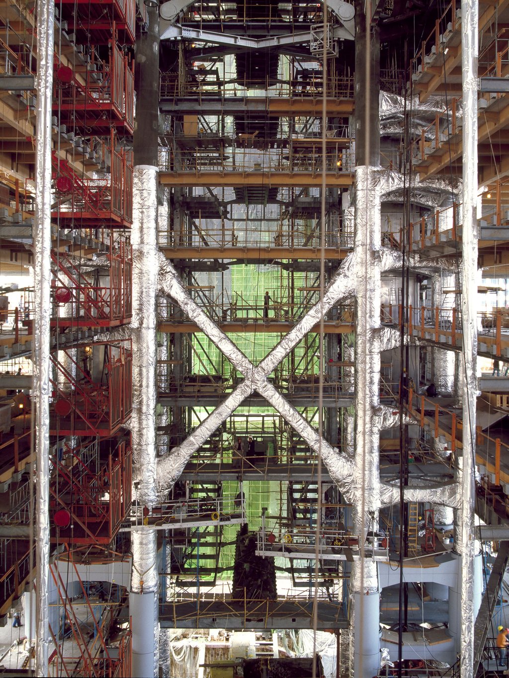 The cathedral-like atrium, 12 storeys and 55 metres high, as measured from ground level, starts to emerge, in January 1984. The three-storey cross-bracing and mast sections show their internal aluminium, fire-protection cladding. Behind are the link bridges and support structure for the lift shafts. Photo: Ian Lambot The cathedral-like atrium, 12 storeys and 55 metres high, as measured from ground level, starts to emerge, in January 1984. The three-storey cross-bracing and mast sections show their internal aluminium, fire-protection cladding. Behind are the link bridges and support structure for the lift shafts. Photo: Ian Lambot