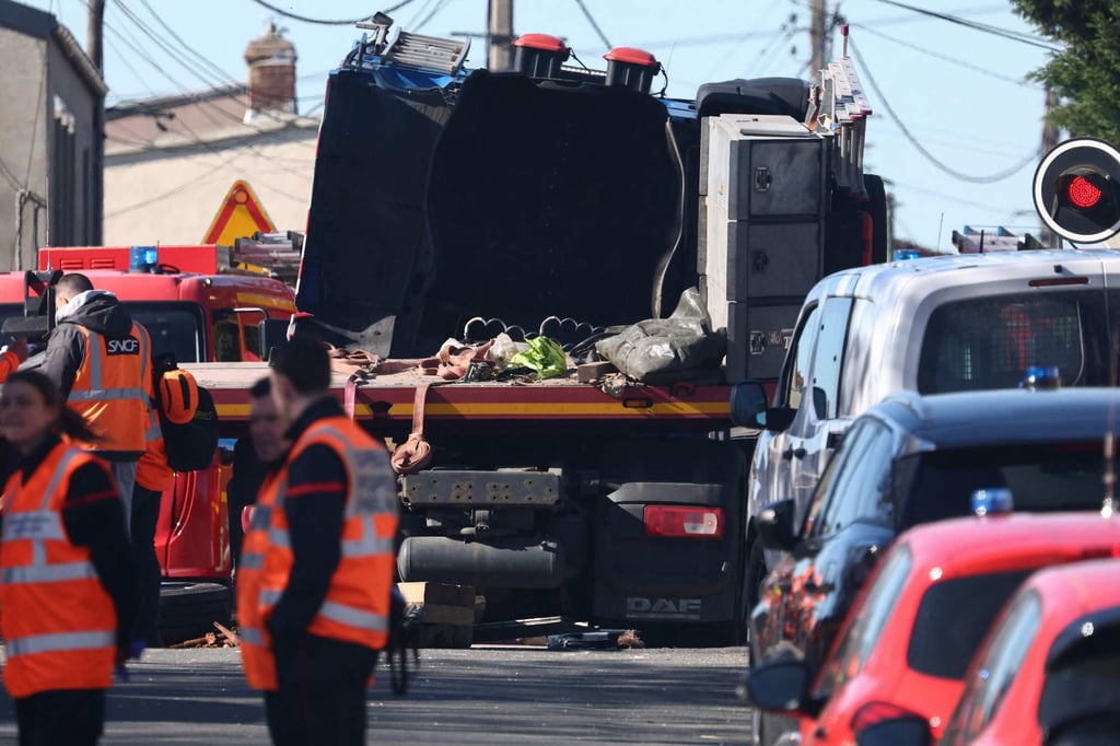Bombeiros alinham-se na estrada após uma colisão entre um trem TGV e um caminhão. Foto: AFP Bombeiros alinham-se na estrada após uma colisão entre um trem TGV e um caminhão. Foto: AFP